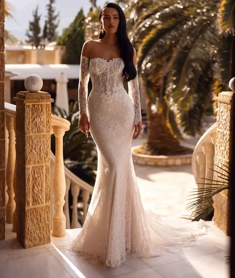 model is wearing a strapless lace fit and flare bridal gown with detachable long sleeves